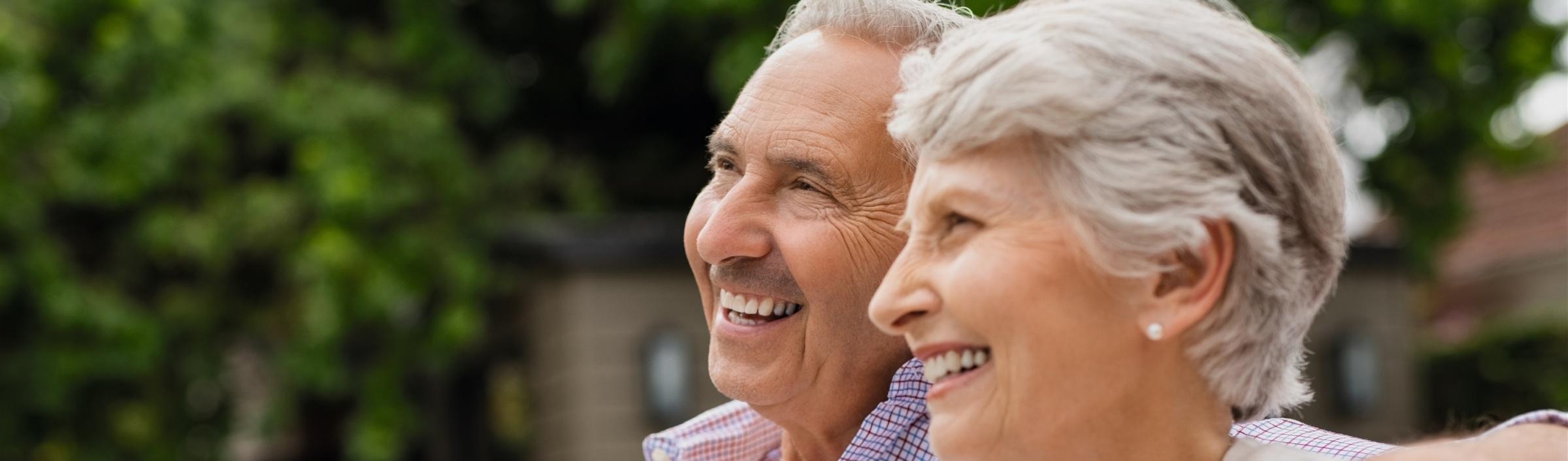 Ein älteres Paar genießt es, gemeinsam auf einer Bank im Freien zu sitzen.