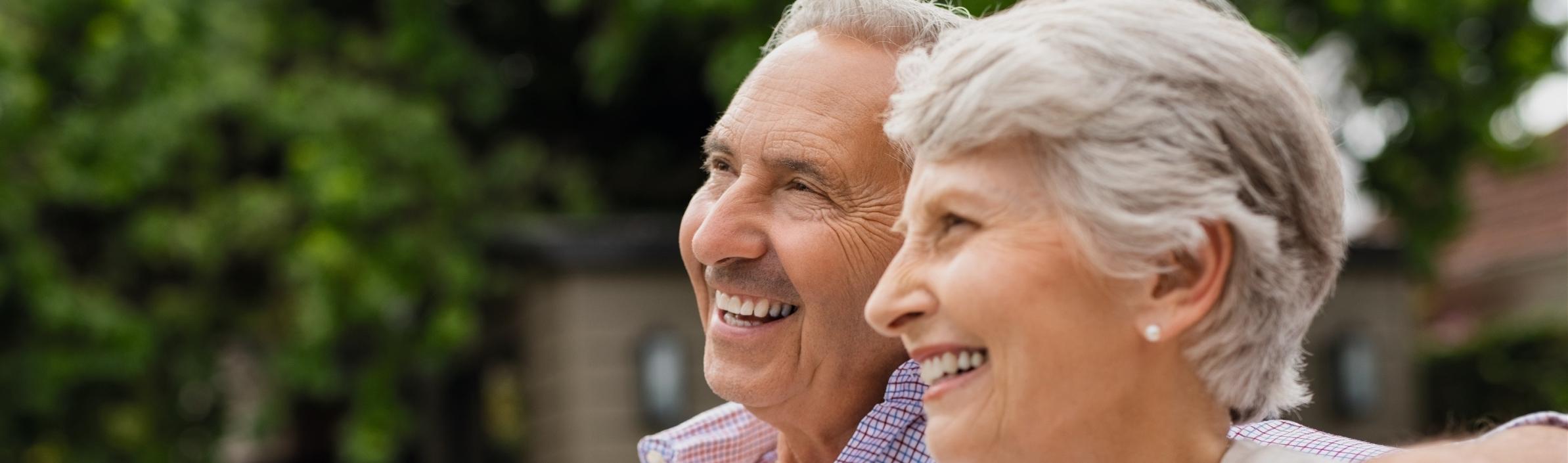 Ein älteres Paar genießt es, gemeinsam auf einer Bank im Freien zu sitzen.