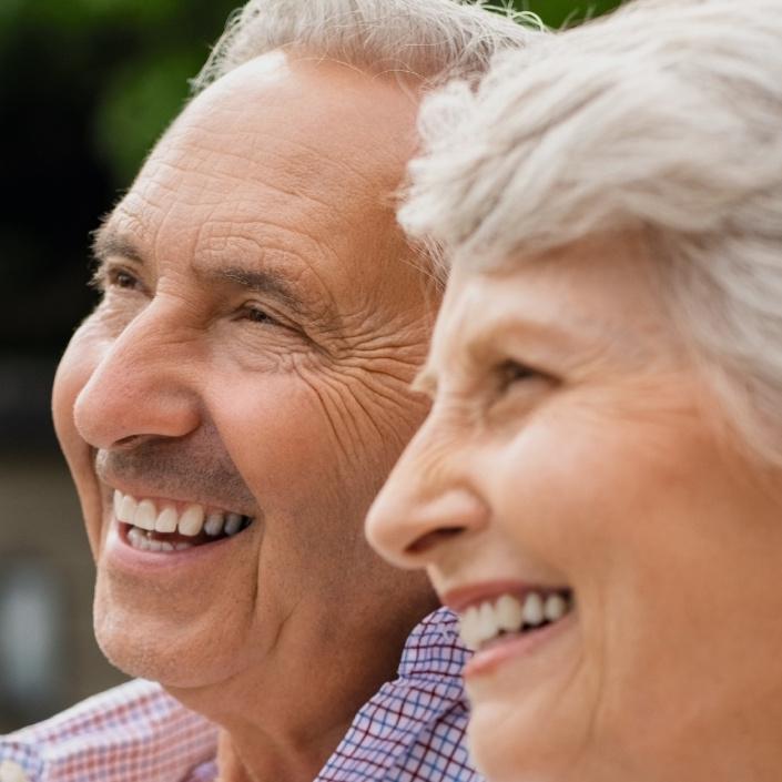 Ein älteres Paar genießt es, gemeinsam auf einer Bank im Freien zu sitzen.