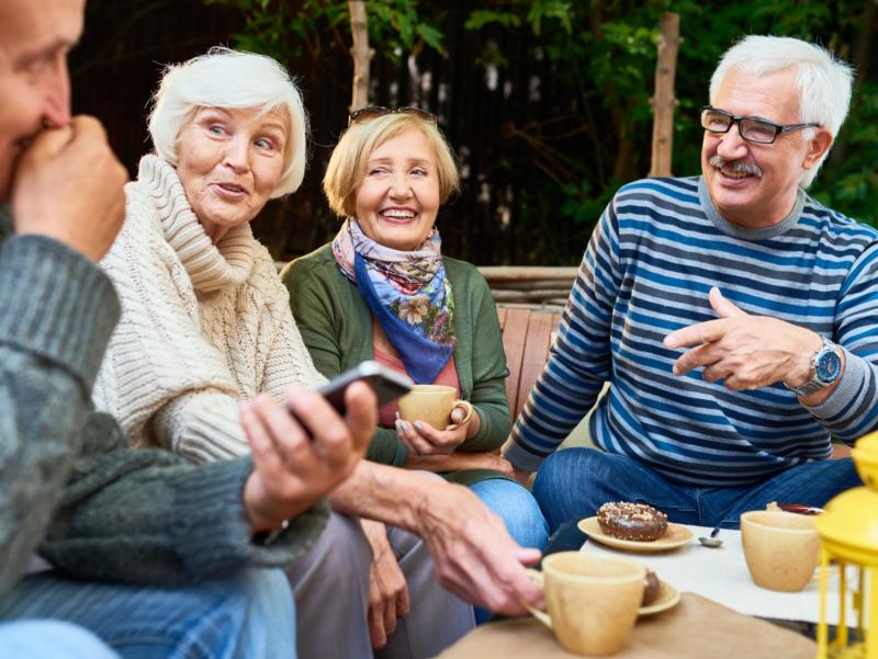 shutterstock_1059449363_SeventyFour_Senioren_Seniorinnen_unterhalten_sich_bei_Kaffe_Kuchen_Smartphone_im_Vordergrund_frei