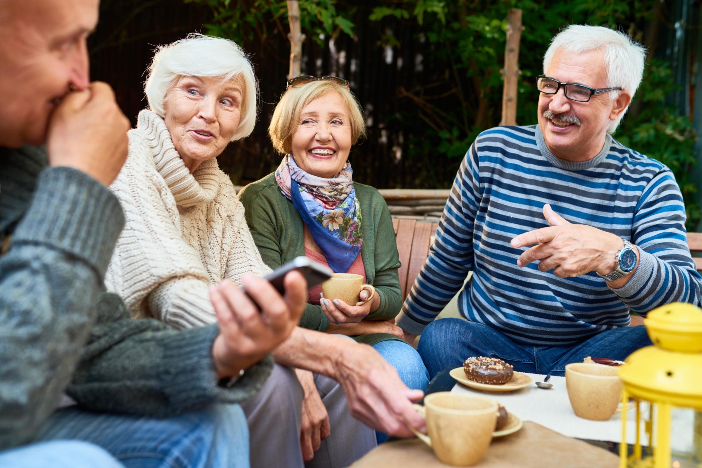 shutterstock_1059449363_SeventyFour_Senioren_Seniorinnen_unterhalten_sich_bei_Kaffe_Kuchen_Smartphone_im_Vordergrund_frei