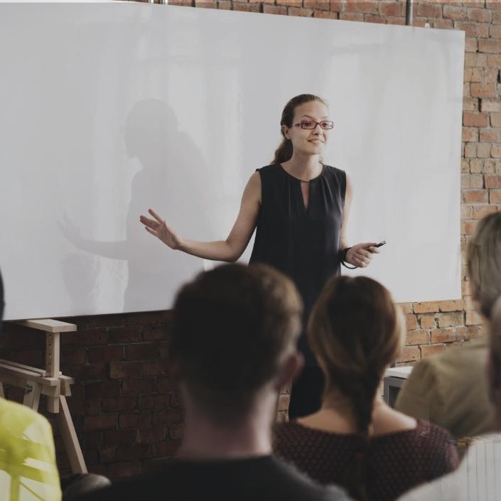 Erwachsenenbildung - Kursleiterin referiert vor einem Smartboard, die Kursgruppe hört aufmerksam zu