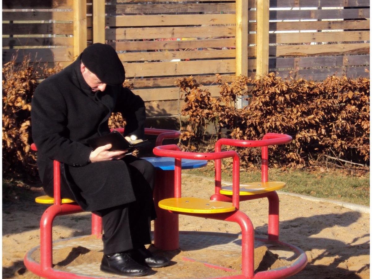 das Alter, Alleinsein, Einsamkeit, alter Mann, ohne Ansprache, in Gedanken versunken,  abwesend sein, in der Sonne sitzen,  lesen,   Kinderkarussell, auf dem Spielplatz,  Fotowettbewerb 2014 Ex-Bild-DB-ID: 12199