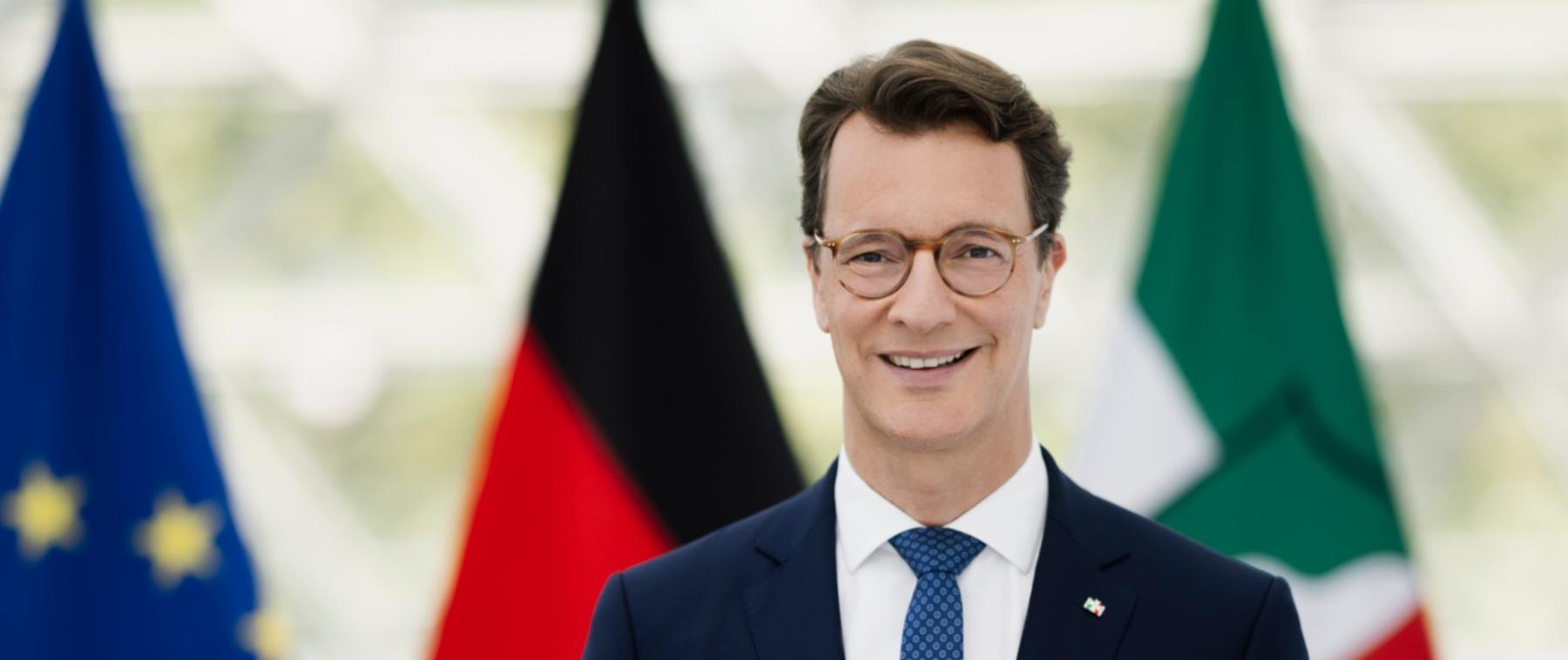Ministerpräsident Hendrik-Wüst, im Hintergrund die Flaggen von Europa, Deutschland und Nordrhein-Westfalen