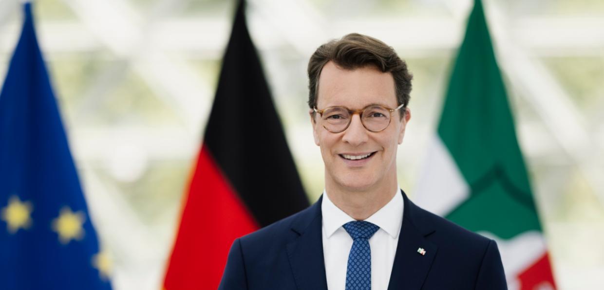 Ministerpräsident Hendrik Wüst, im Hintergrund die Flaggen von Europa, Deutschland und Nordrhein-Westfalen