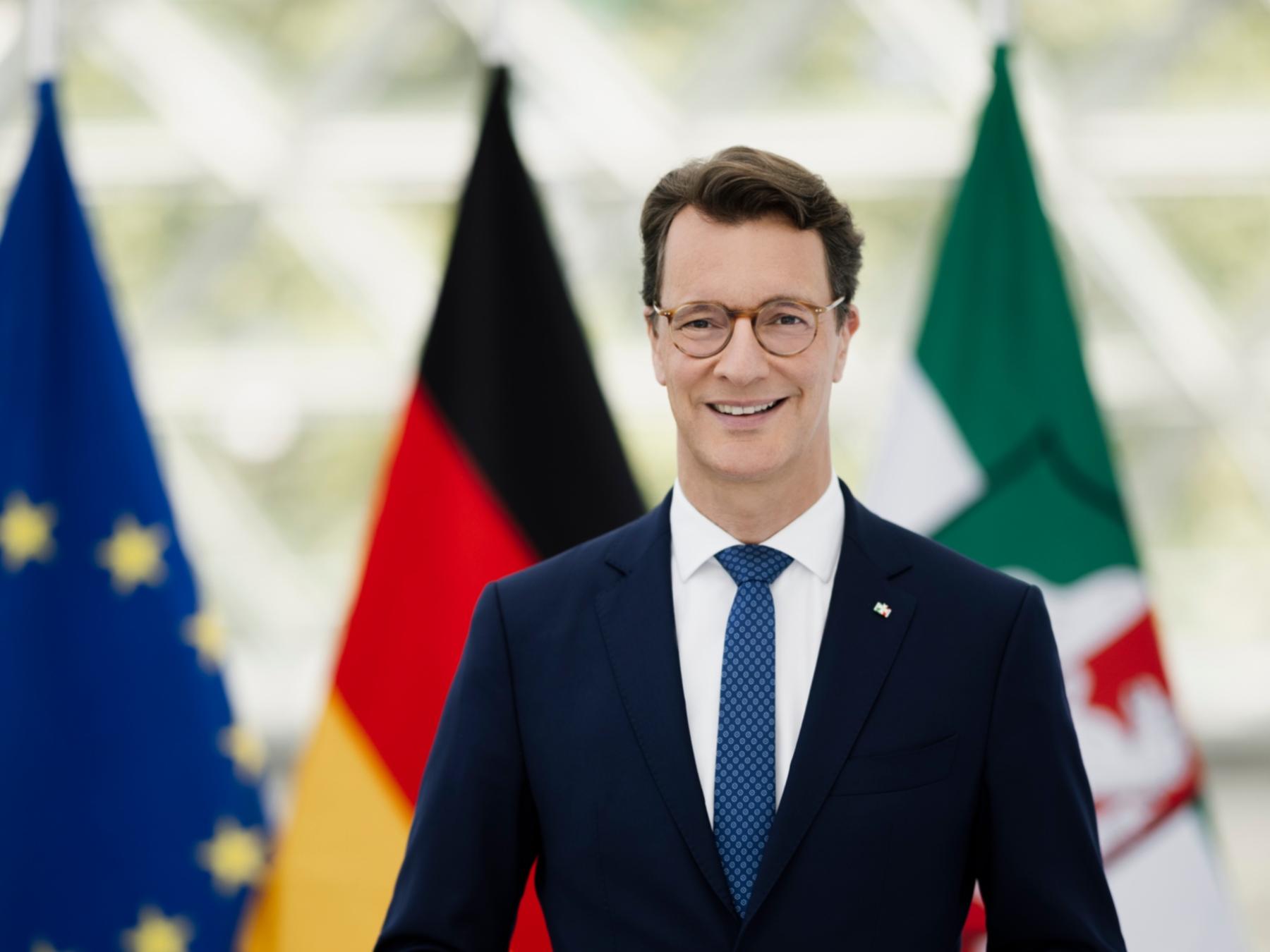 Ministerpräsident Hendrik-Wüst, im Hintergrund die Flaggen von Europa, Deutschland und Nordrhein-Westfalen