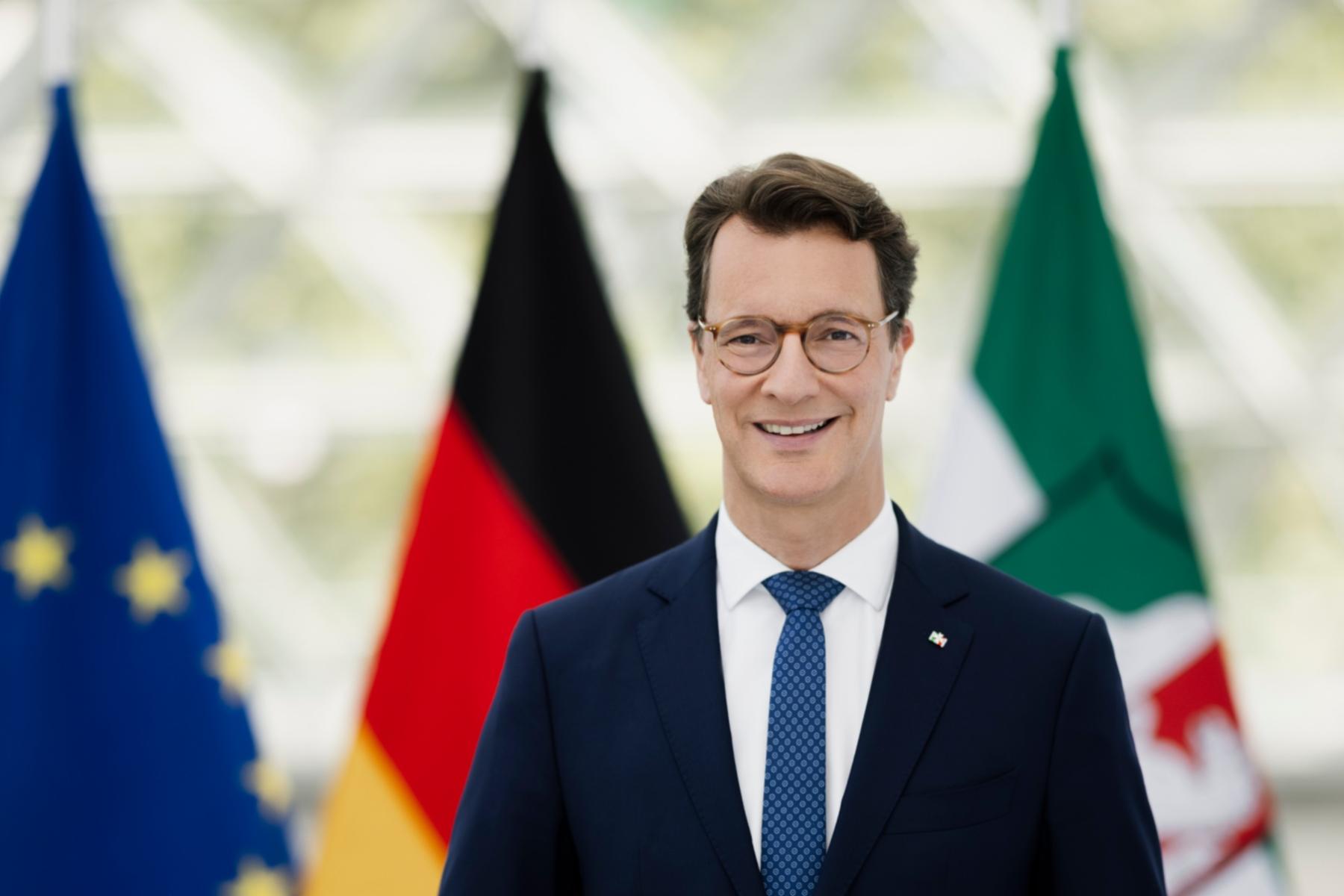 Ministerpräsident Hendrik Wüst, im Hintergrund die Flaggen von Europa, Deutschland und Nordrhein-Westfalen