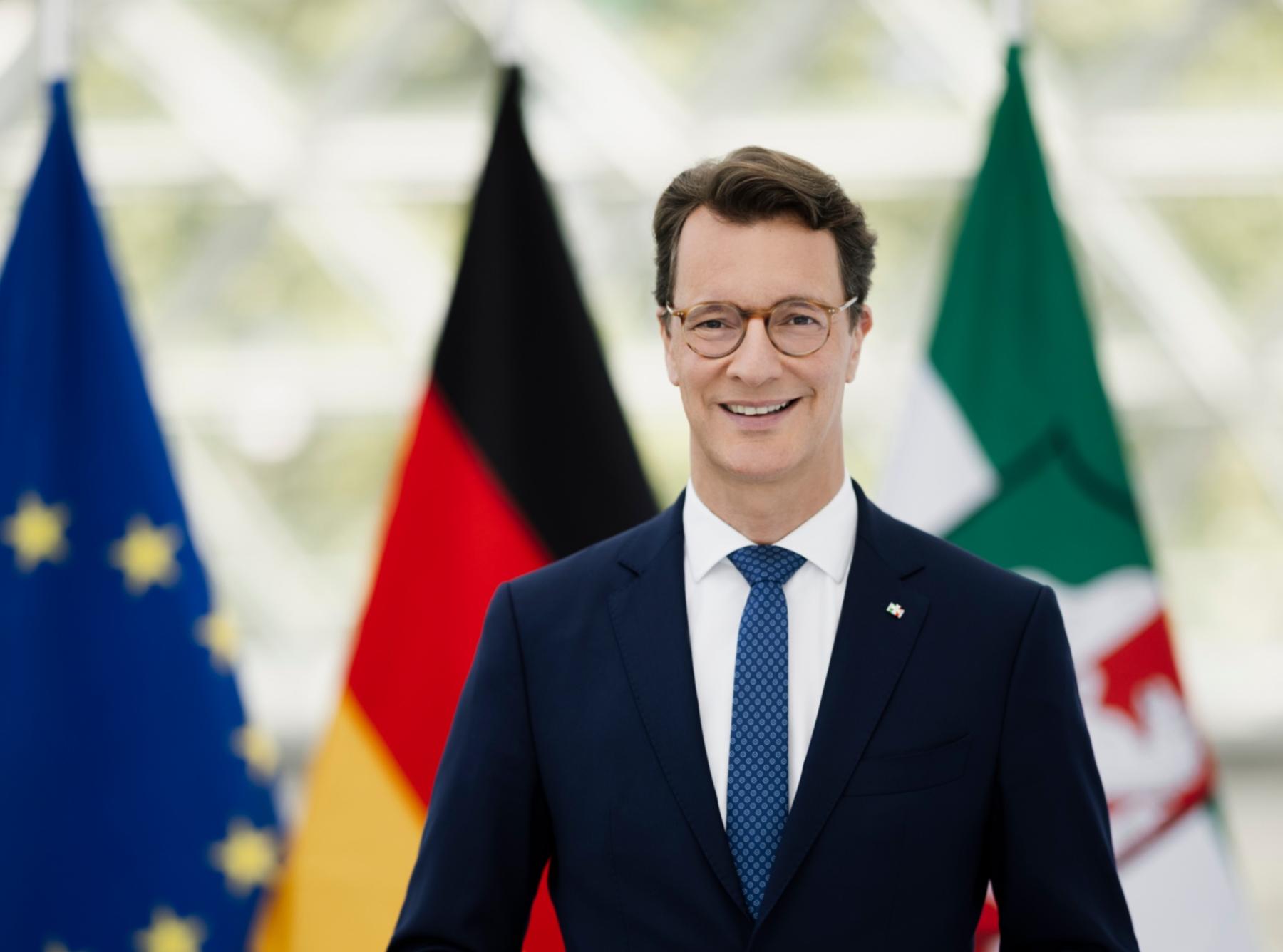 Ministerpräsident Hendrik-Wüst, im Hintergrund die Flaggen von Europa, Deutschland und Nordrhein-Westfalen