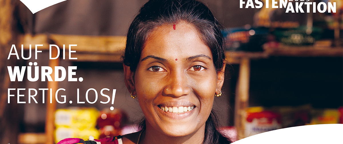Logo der Misereor Fastenaktion 2025 Auf die Würde. Fertig. Los! Eine junge Frau aus der Gemeinschaft der Hochland-Tamilen in Sri Lanka schaut Sie freundlich an.
