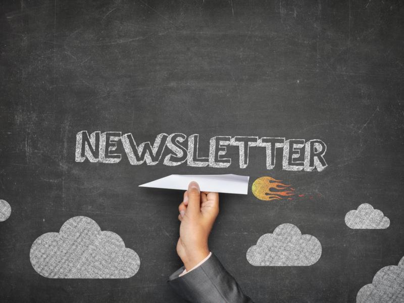 Papierrakete fliegt über einen Tafelhimmel und kündigt einen Newsletter an