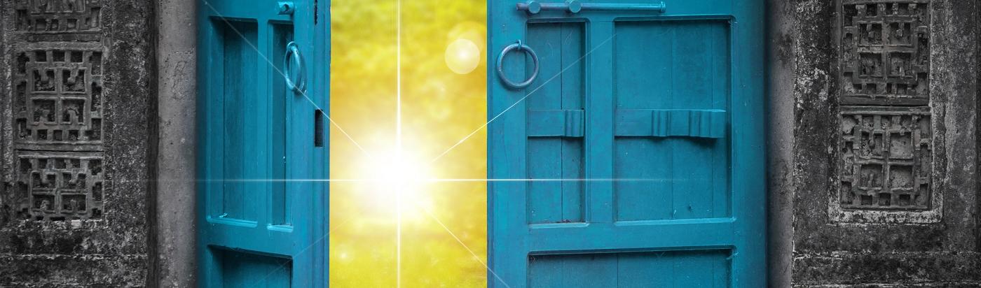 Eine Tür öffnet sich hin auf eine strahlende Sonne.