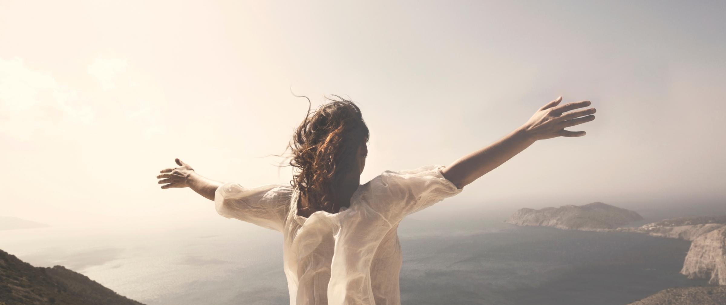 shutterstock_1145153555_Cristina Conti_Frau_entspannt_mit_tollem_Ausblick_Gebirge_Meer_Natur_frei