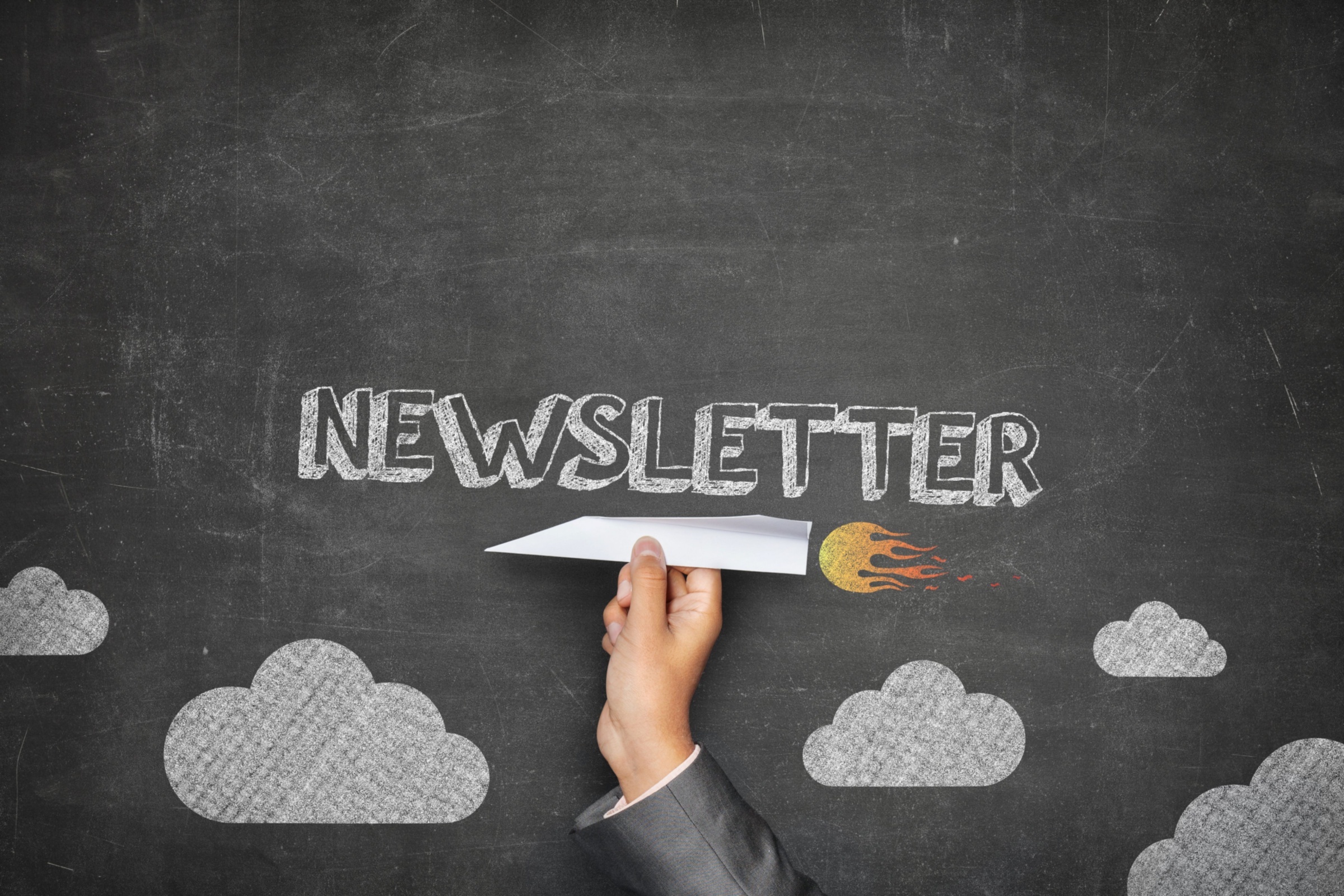 Papierrakete fliegt über einen Tafelhimmel und kündigt einen Newsletter an