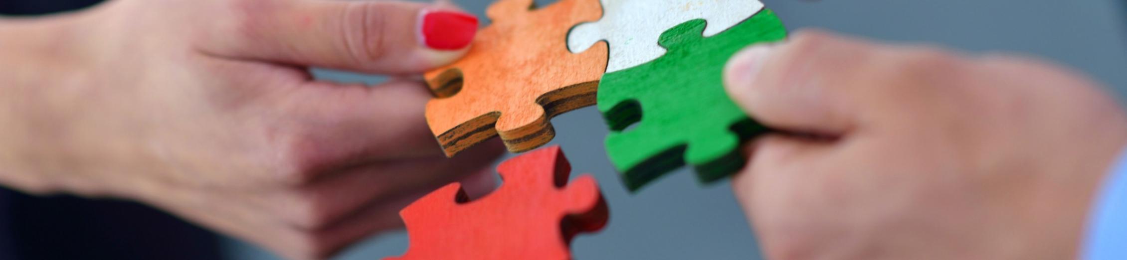 Hände setzen bunte Puzzleteile zusammen.