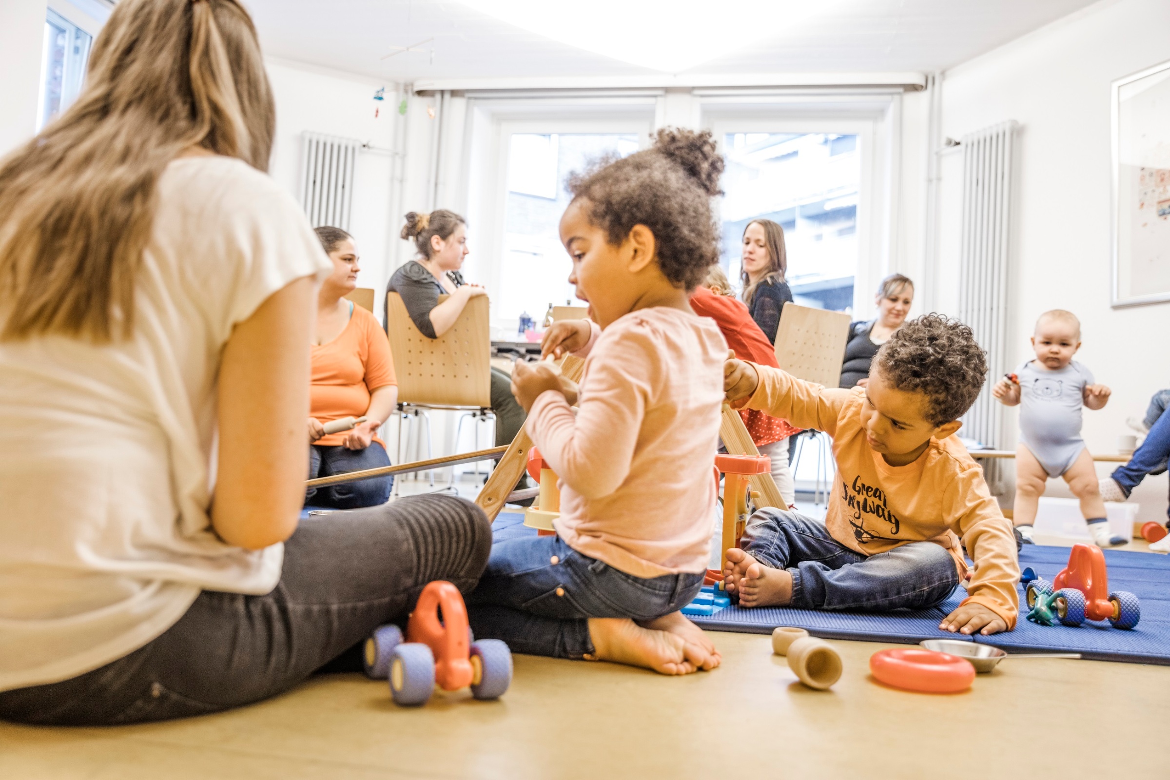 Pikler-Kinder mit Erwachsenen im Kursraum