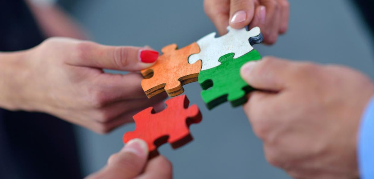 Hände setzen bunte Puzzleteile zusammen.