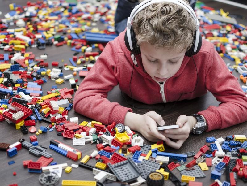 Junge mit Legosteinen und Smartphone