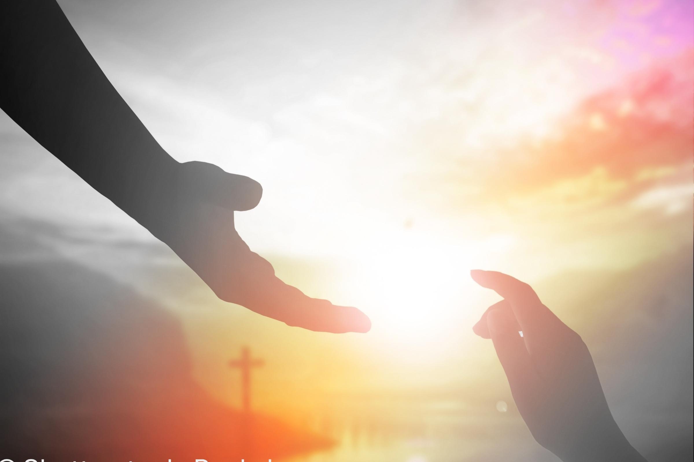 Ausgestreckte Hände vor Kreuz und rotem Himmel