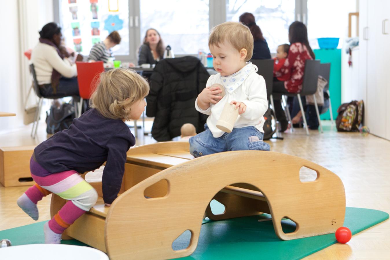 Kinder spielen in einem Eltern-Kind-Kurs auf einem Brückenelement