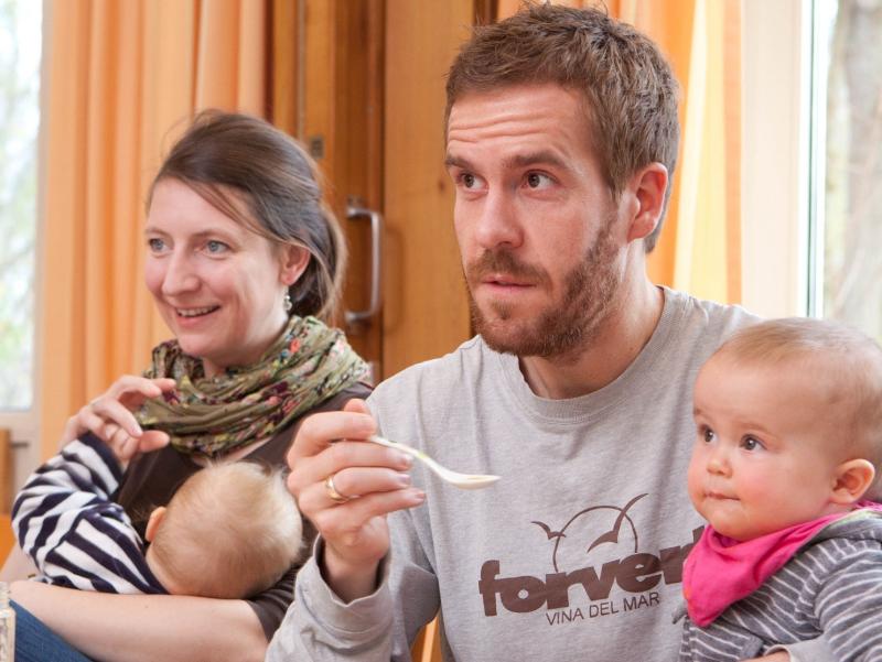 Väter und Mütter mit ihren Kindern auf dem Schoß hören im Eltern-Kind-Kurs aufmerksam zu.